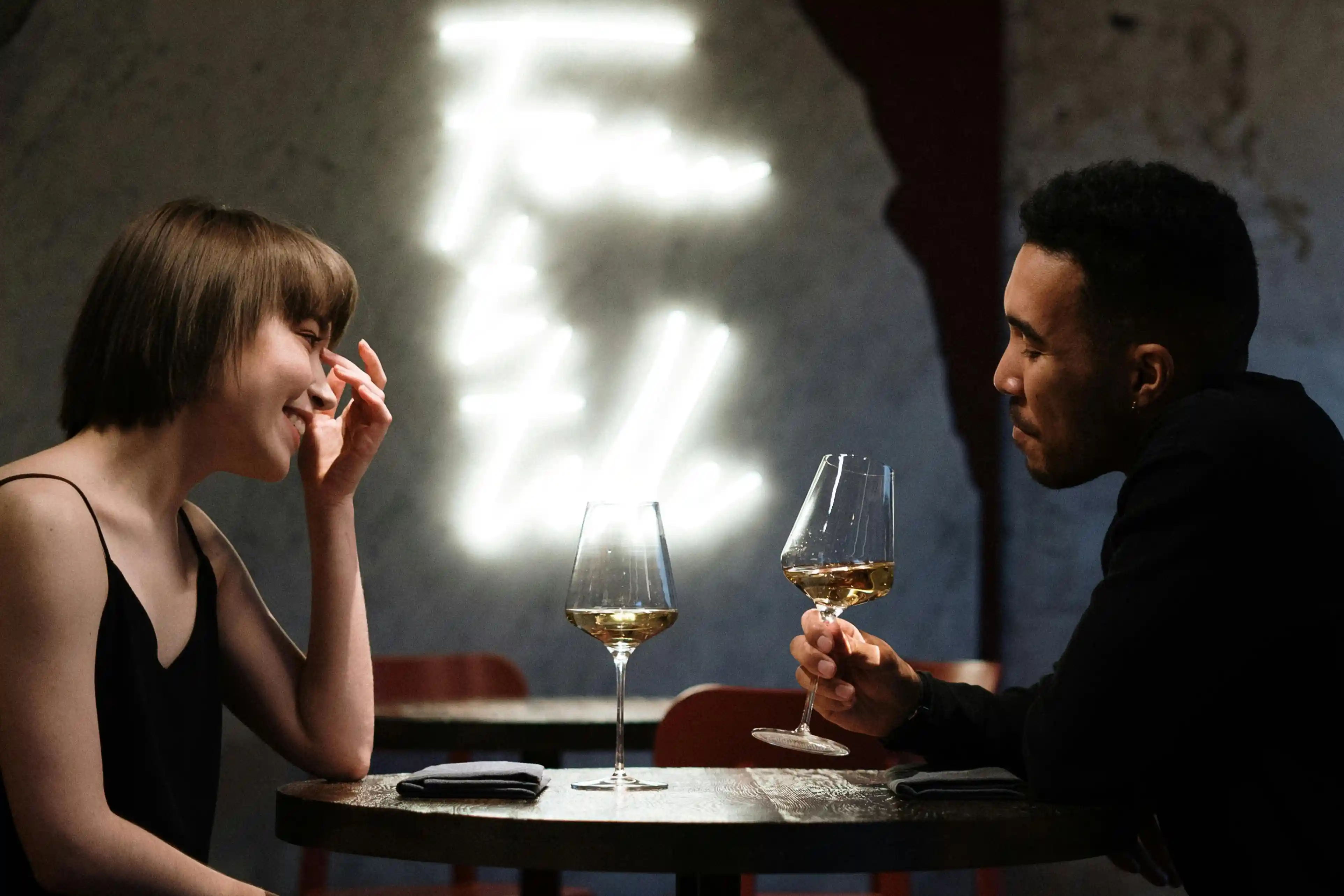 A man and woman sipping wine on a date.