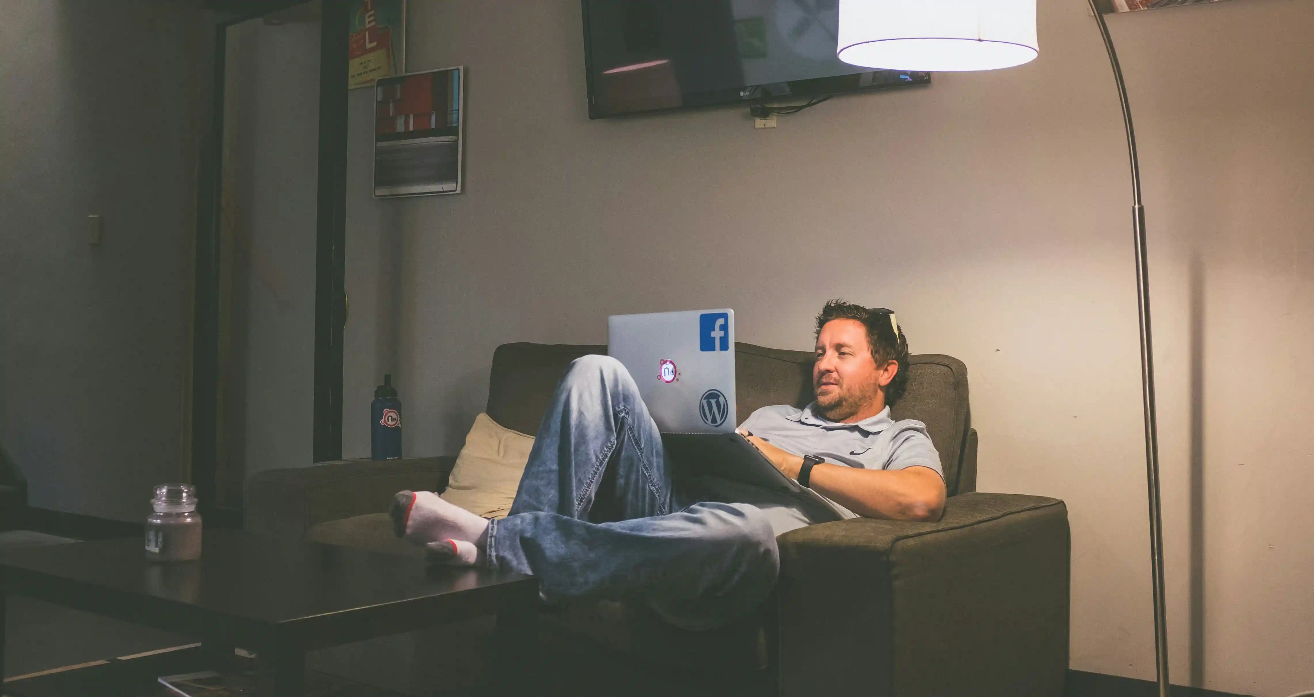 A man lying comfortably on a sofa bed with his laptop on his lap scrolling for some LDR advice