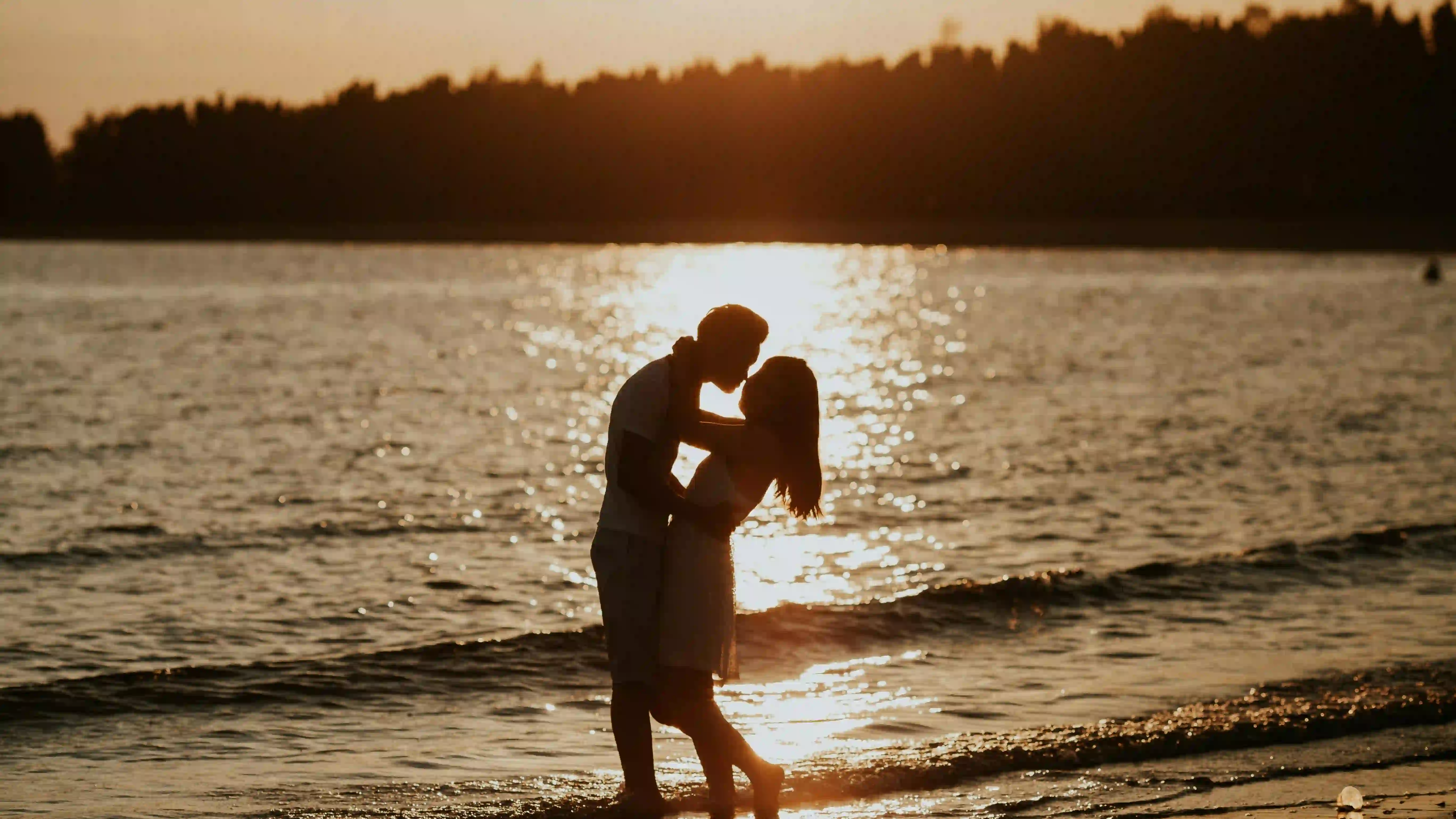 A silhouette of a couple embracing while enjoying the sunset at a beach is an example of amazing date ideas