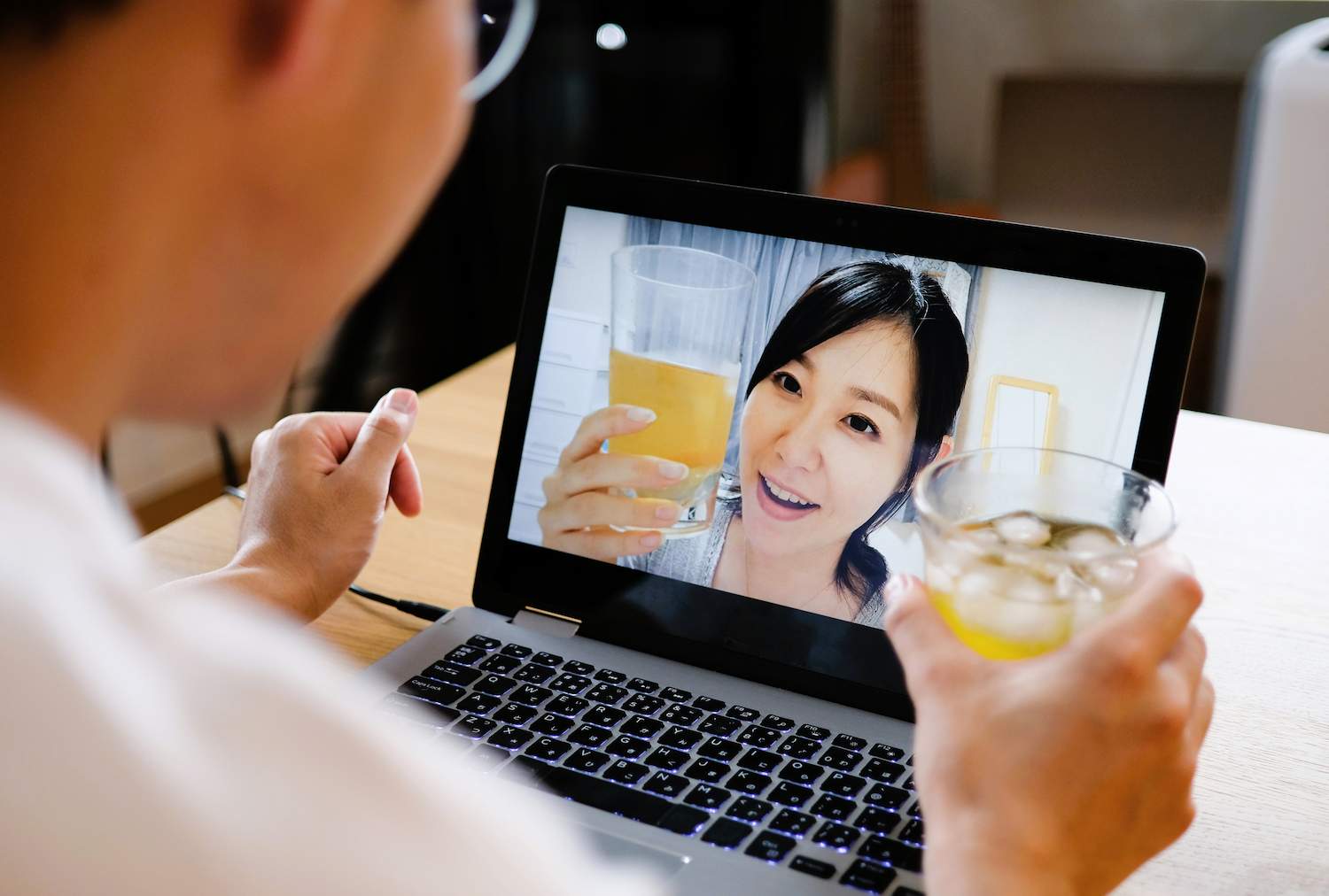 A man toasting to a woman on his laptop screen.