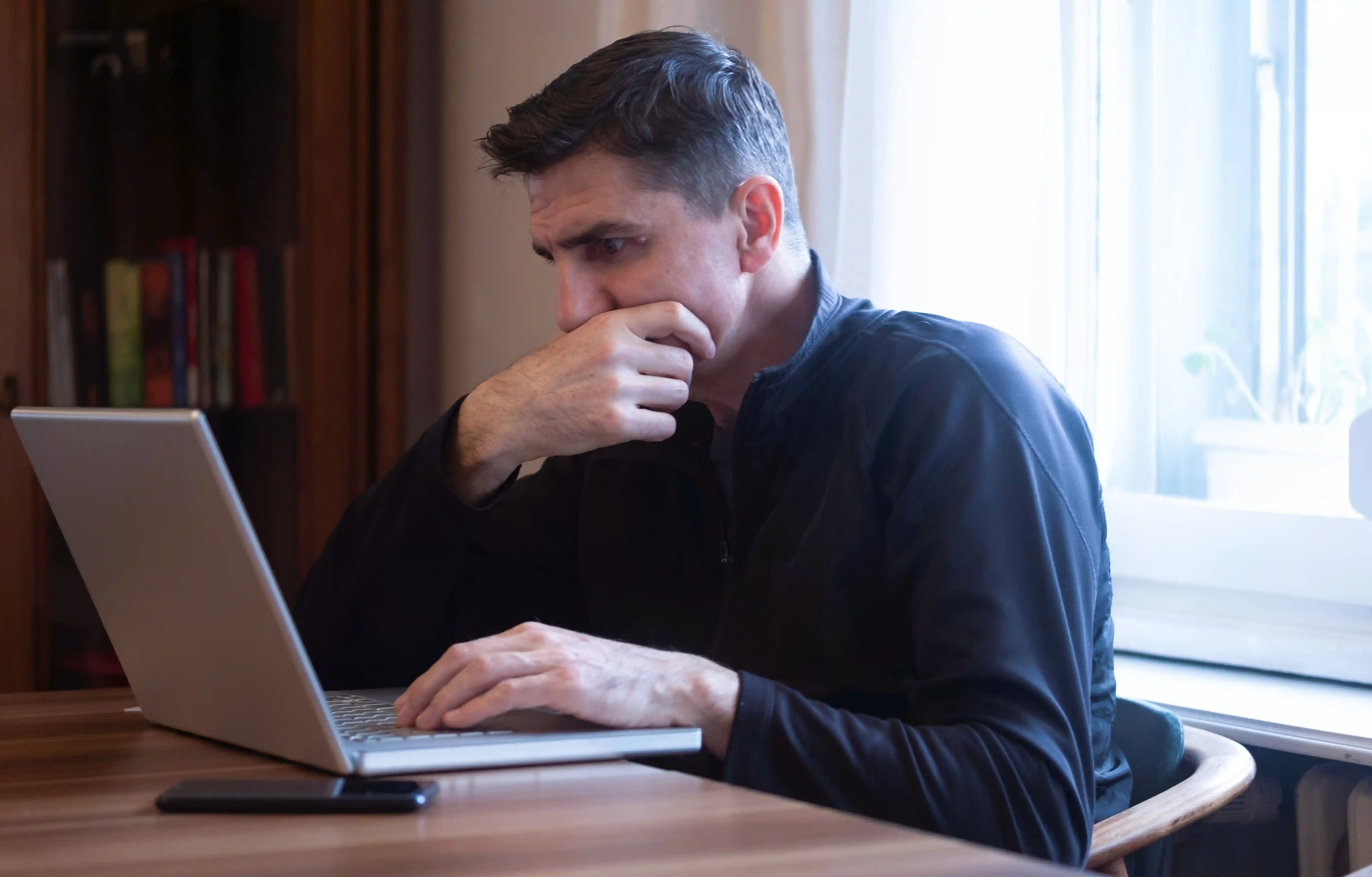 A man looking serious while using a laptop