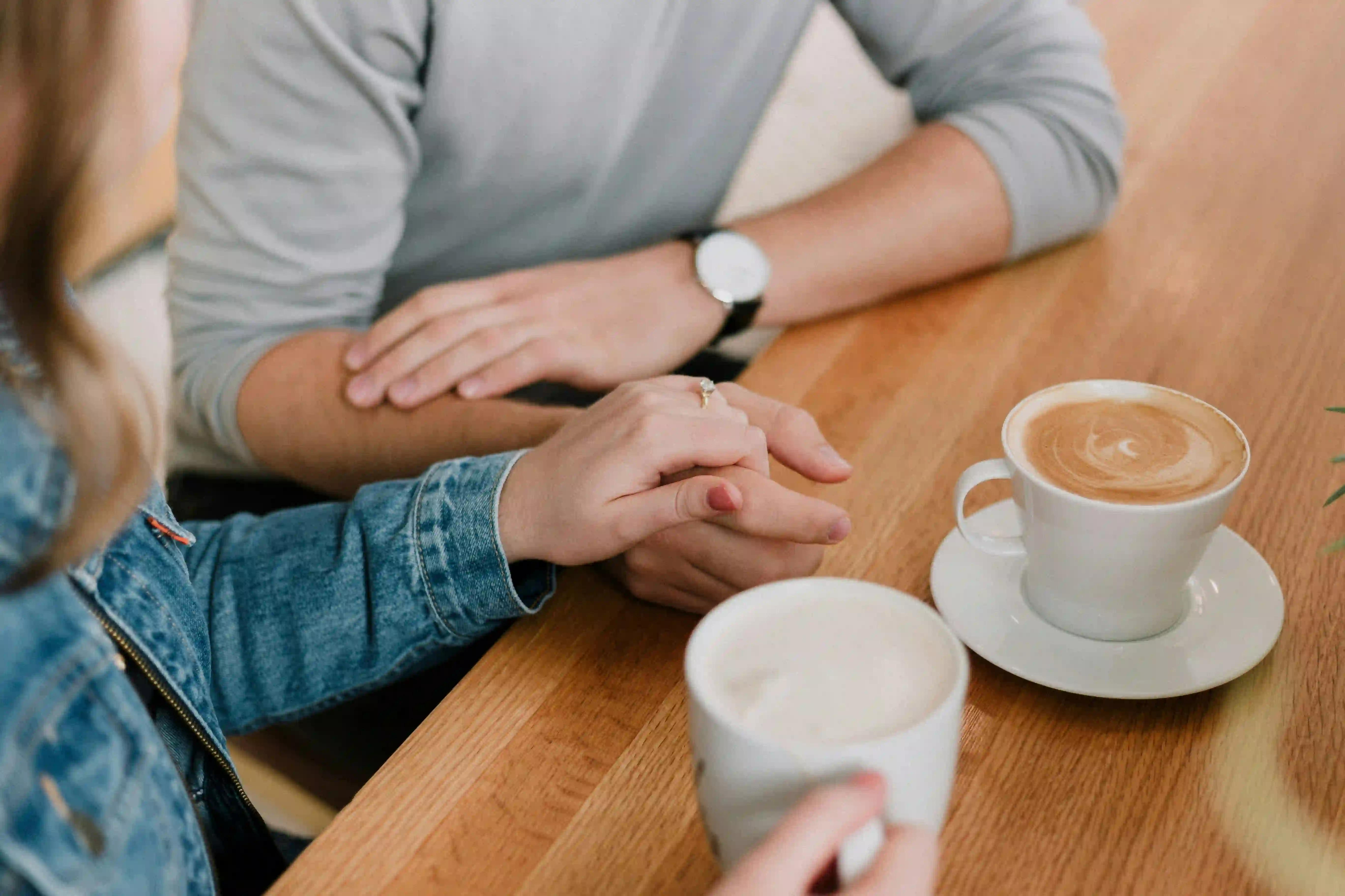 Two people holding hands while enjoying their coffee