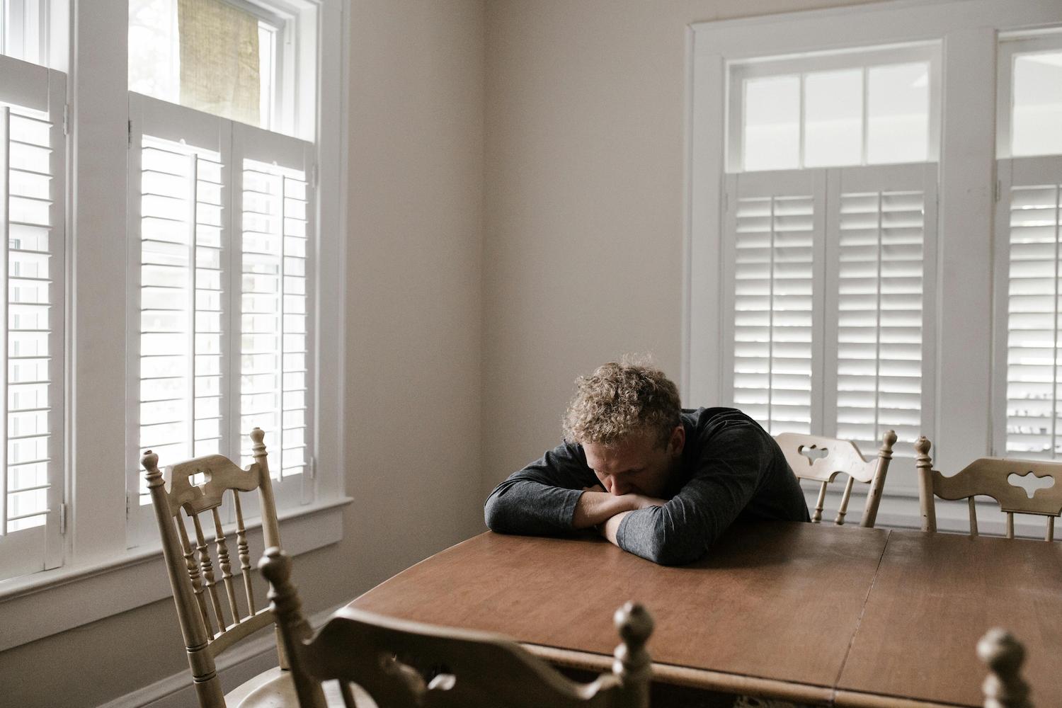 A man crying on his dining table, wondering how to move on.