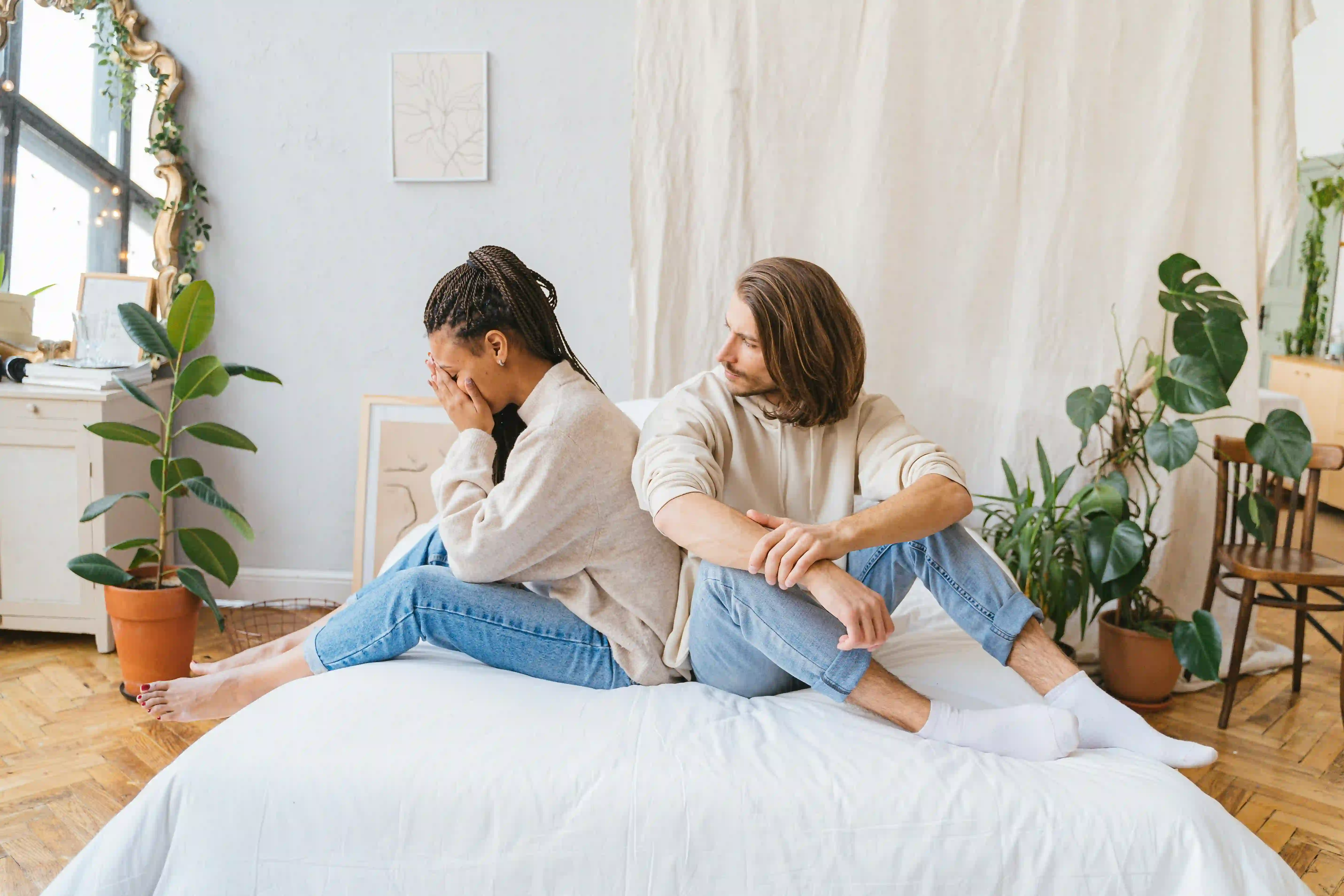 A woman crying in bed while sitting beside a man