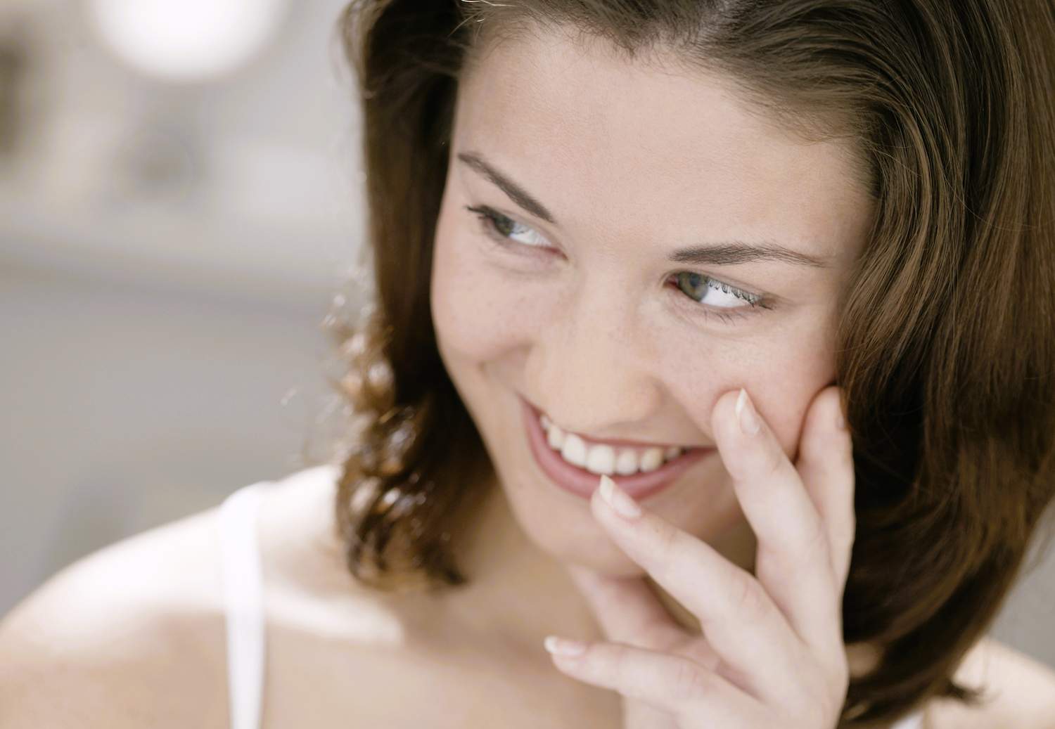 A woman smiling while holding her face