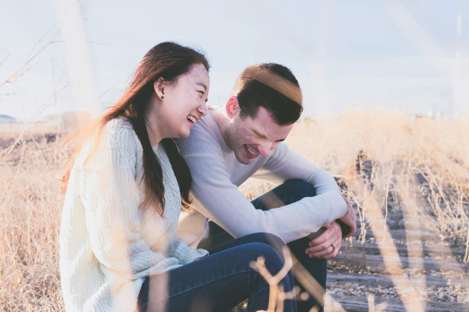 A man laughing together with a woman wondering how to tell if she likes you