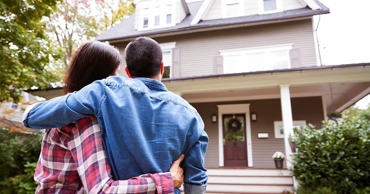 A couple embracing each other while standing in front of a house