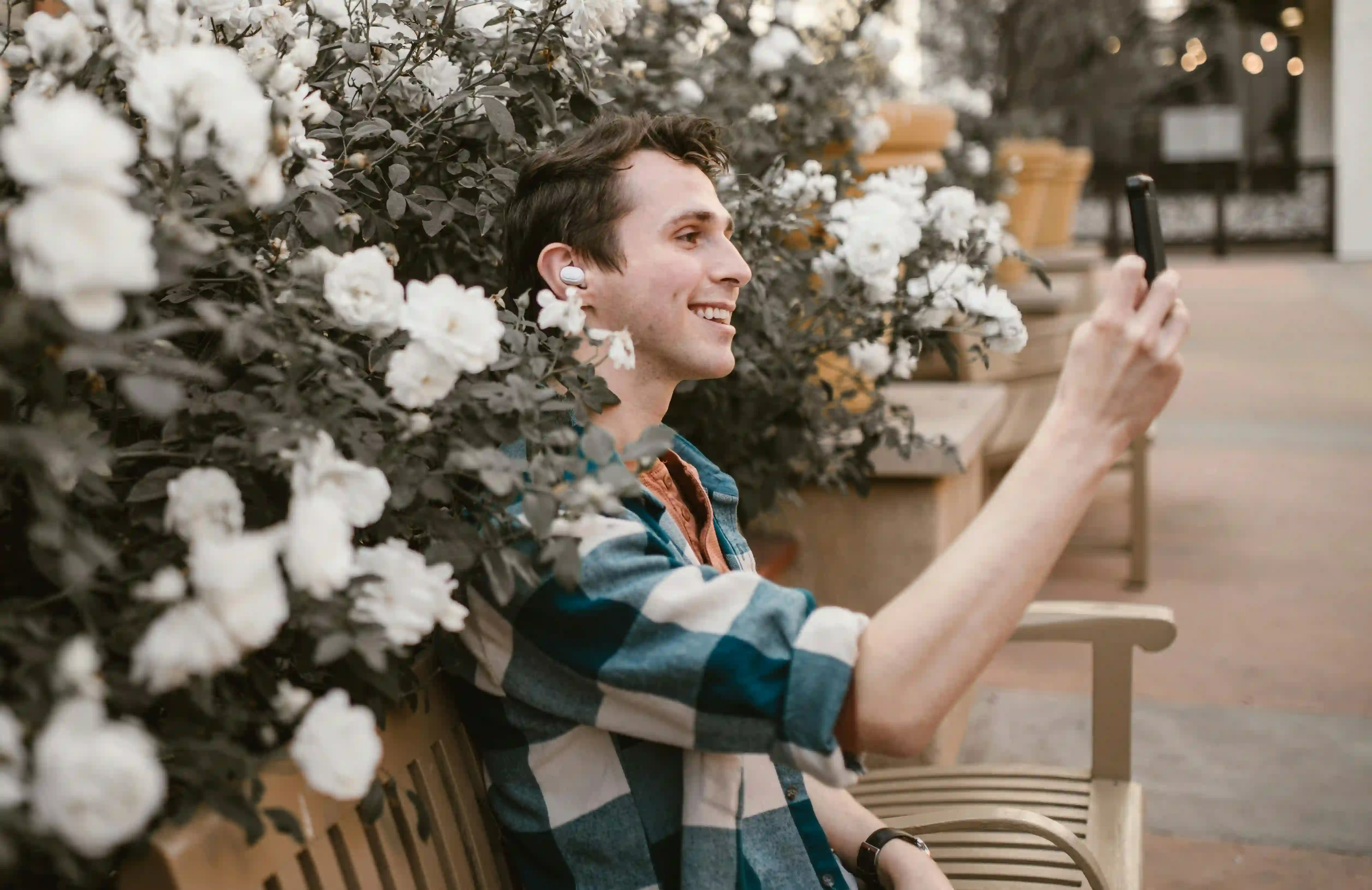 A man in a checkered polo smiling while having a video call using his phone