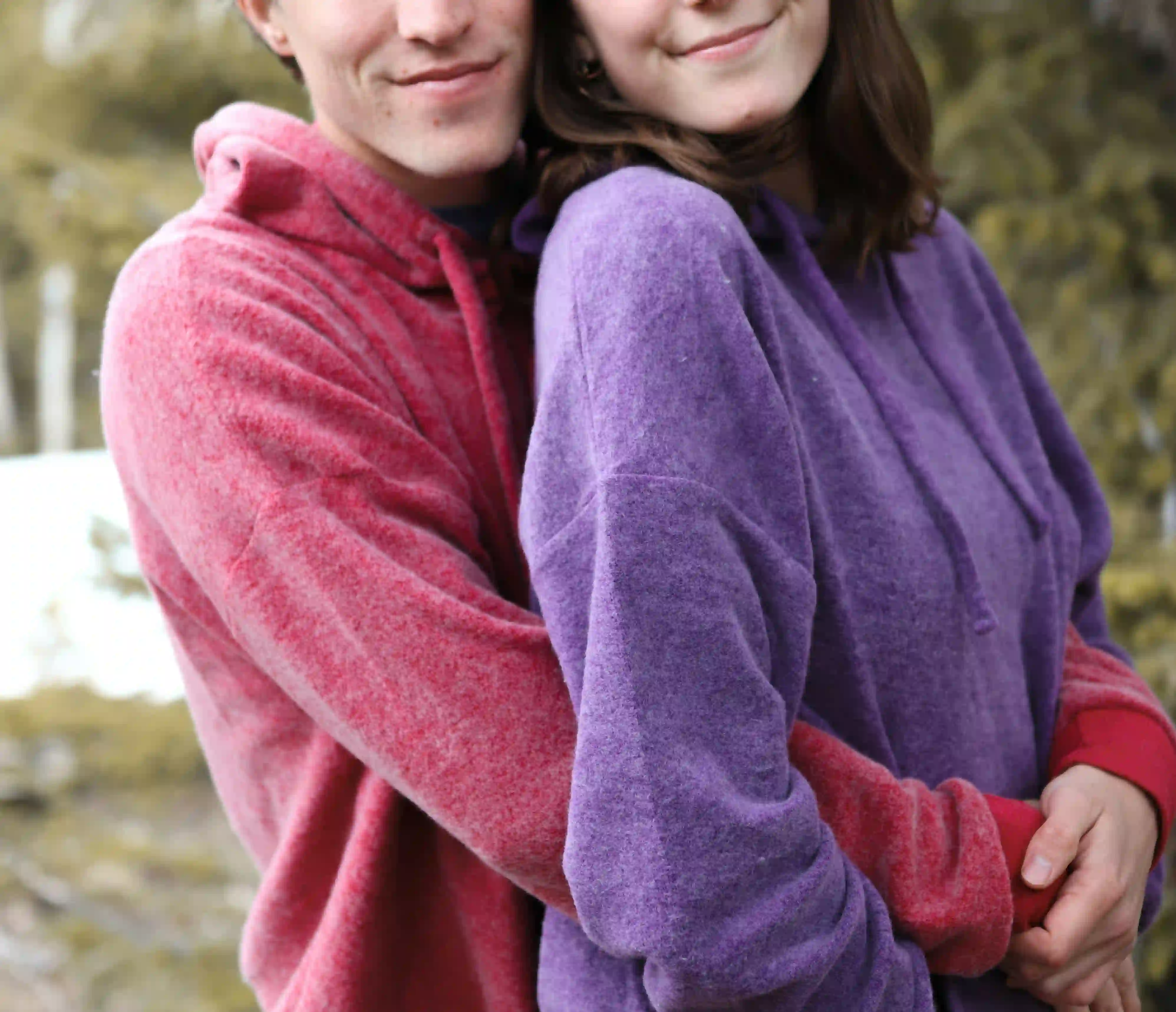 A man hugging a woman behind her back while both wearing hoodies is one of the sweetest long-distance relationship gift ideas