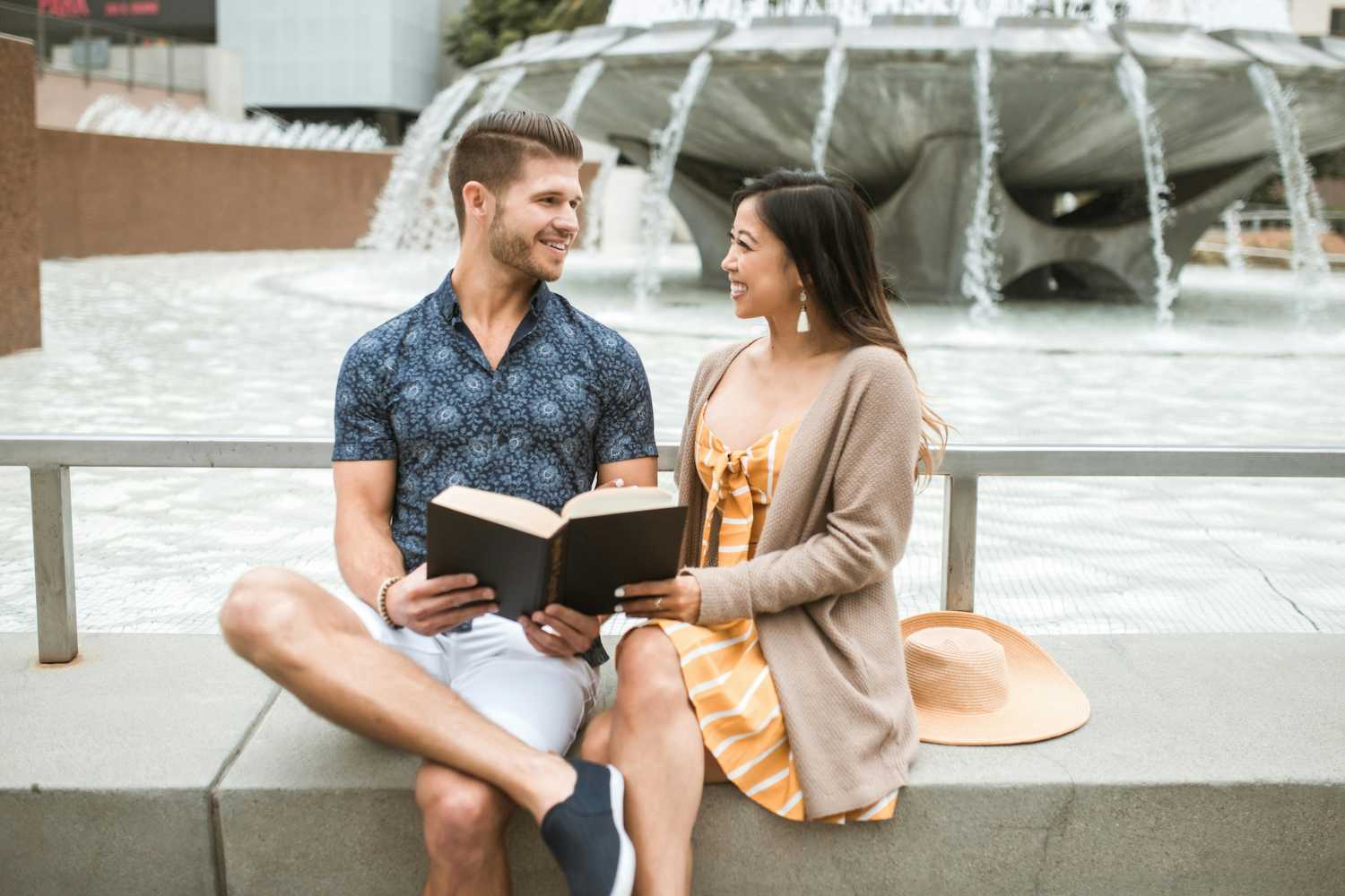 A happy couple sharing a book by a fountain.