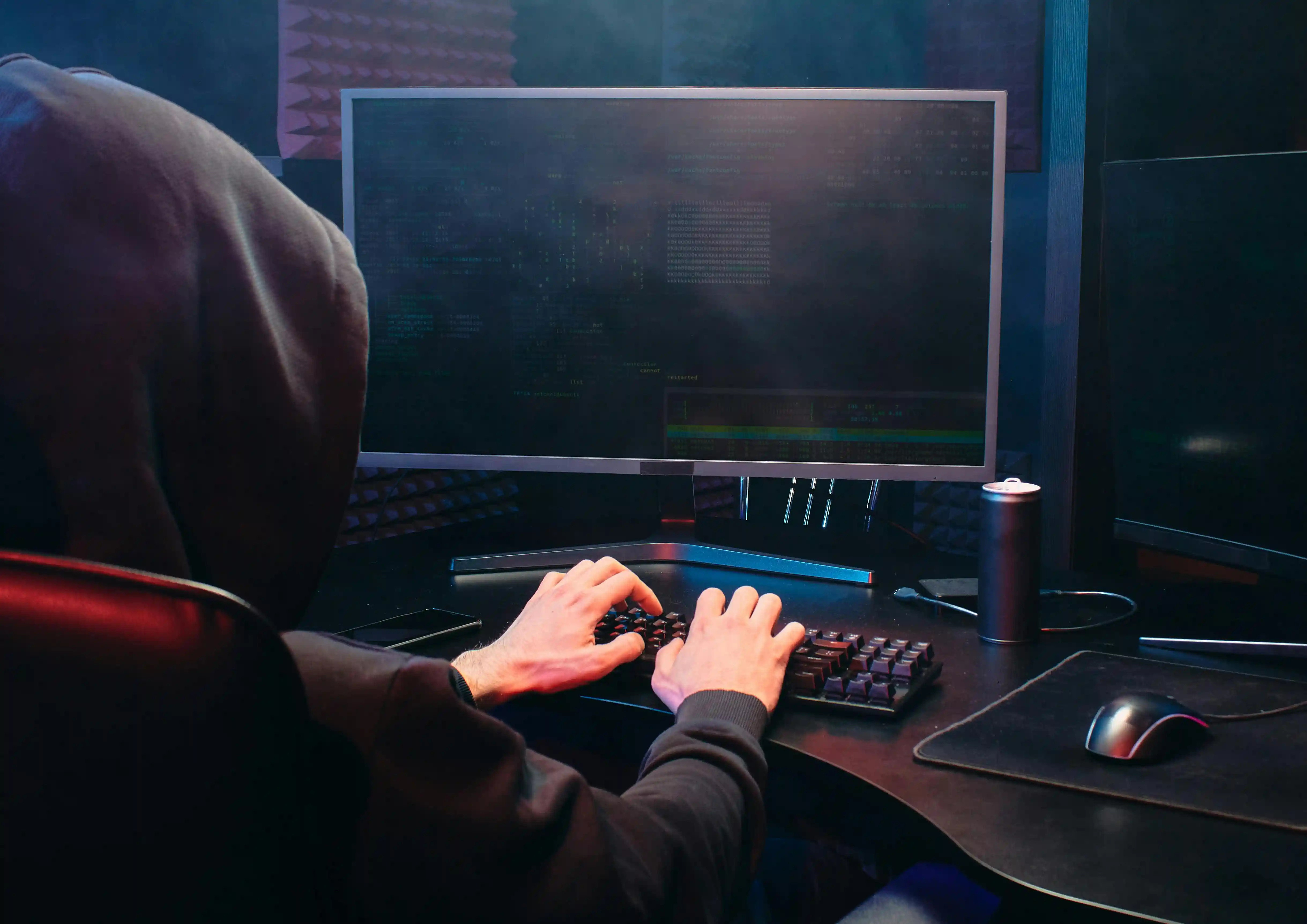 A person in a black hoodie typing on a computer