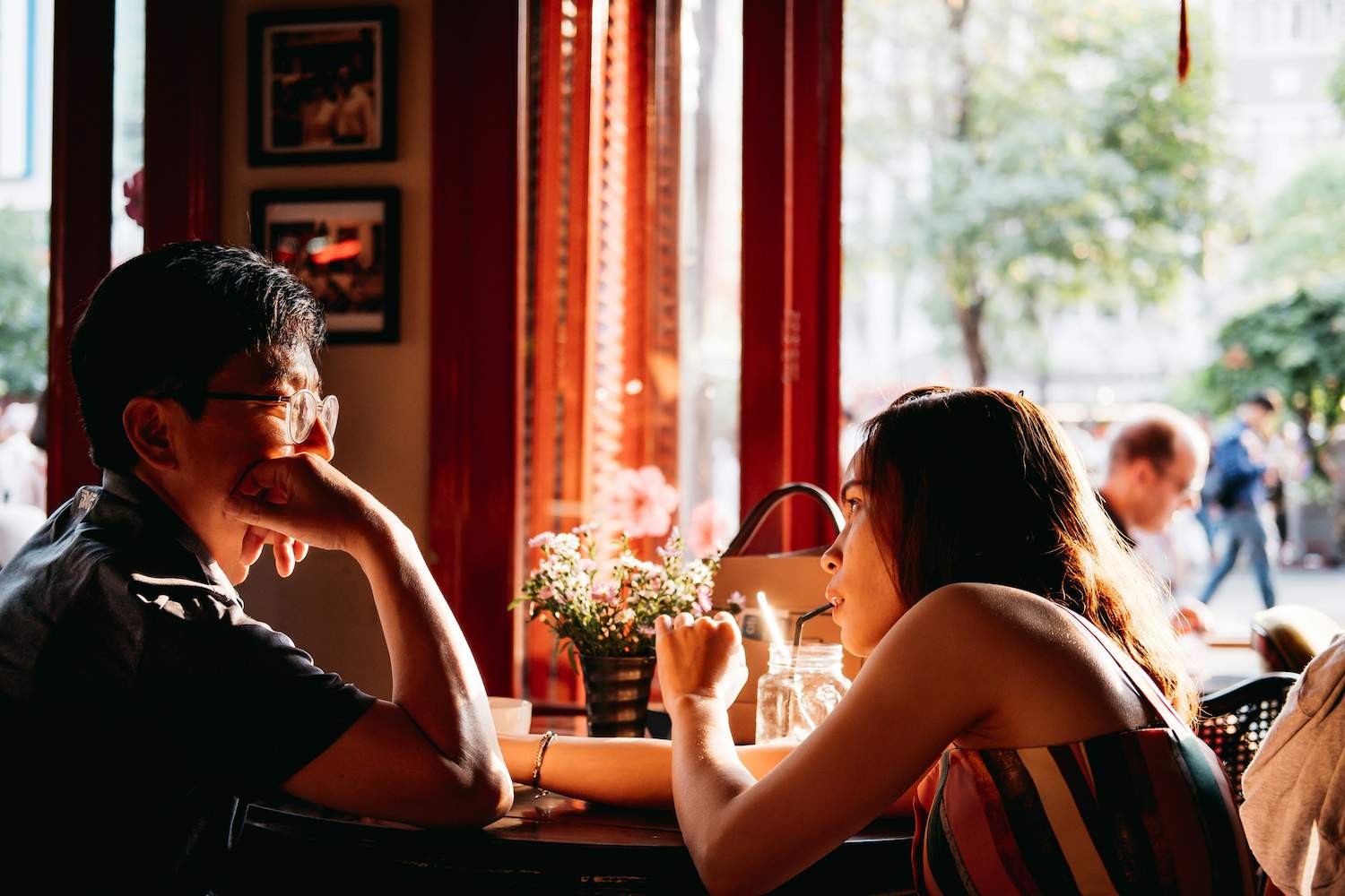 A man facing the woman he is with at the restaurant thinking what are the possible signs a lady is interested in you