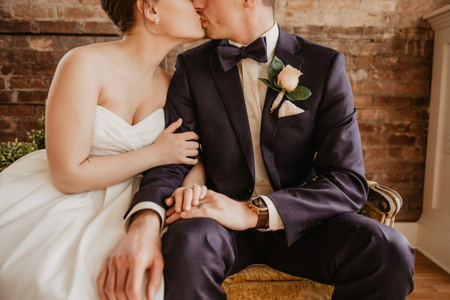 A bride and a groom sitting and sharing a kiss