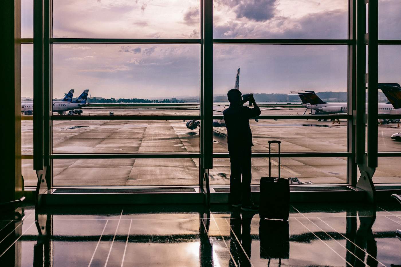 A silhouette of a man taking a photo in the airport with his luggage as he readies to travel
the world