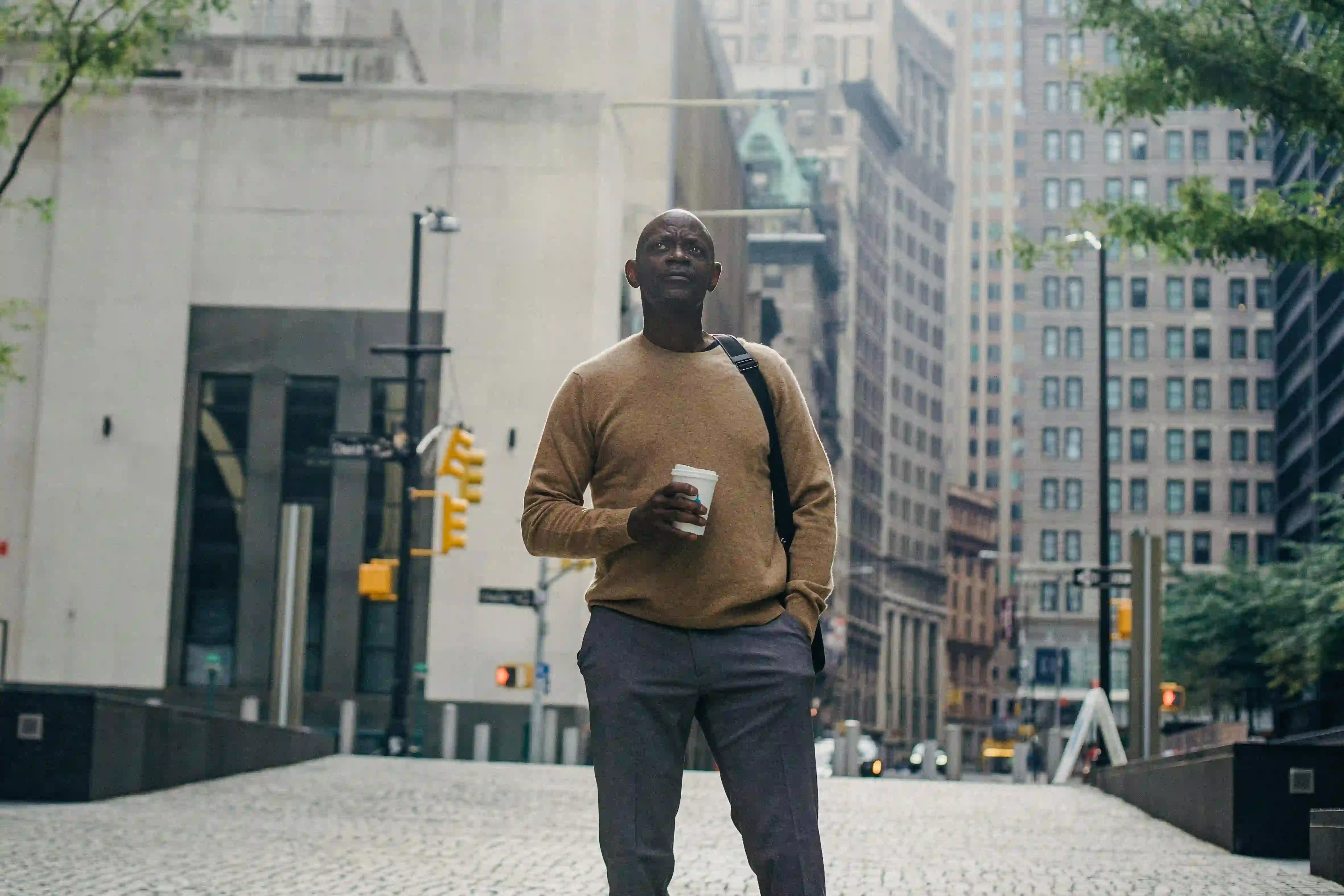 a guy holding a cup of coffee walking on the street