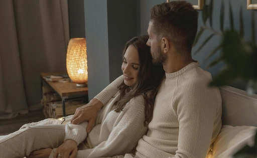 A guy with an arm around his girl while sitting in bed and pondering the issue of what to talk about with your girlfriend